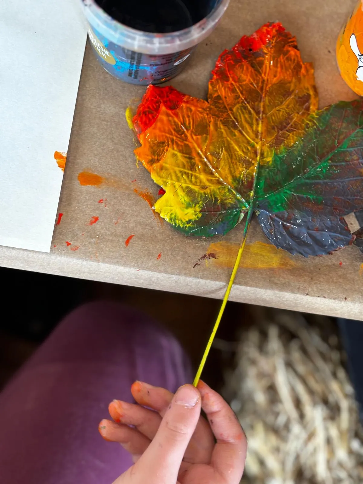 Foglia dipinta con colori caldi e autunnali in un laboratorio creativo